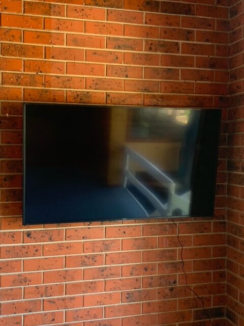 A wall mounted TV on a brick wall