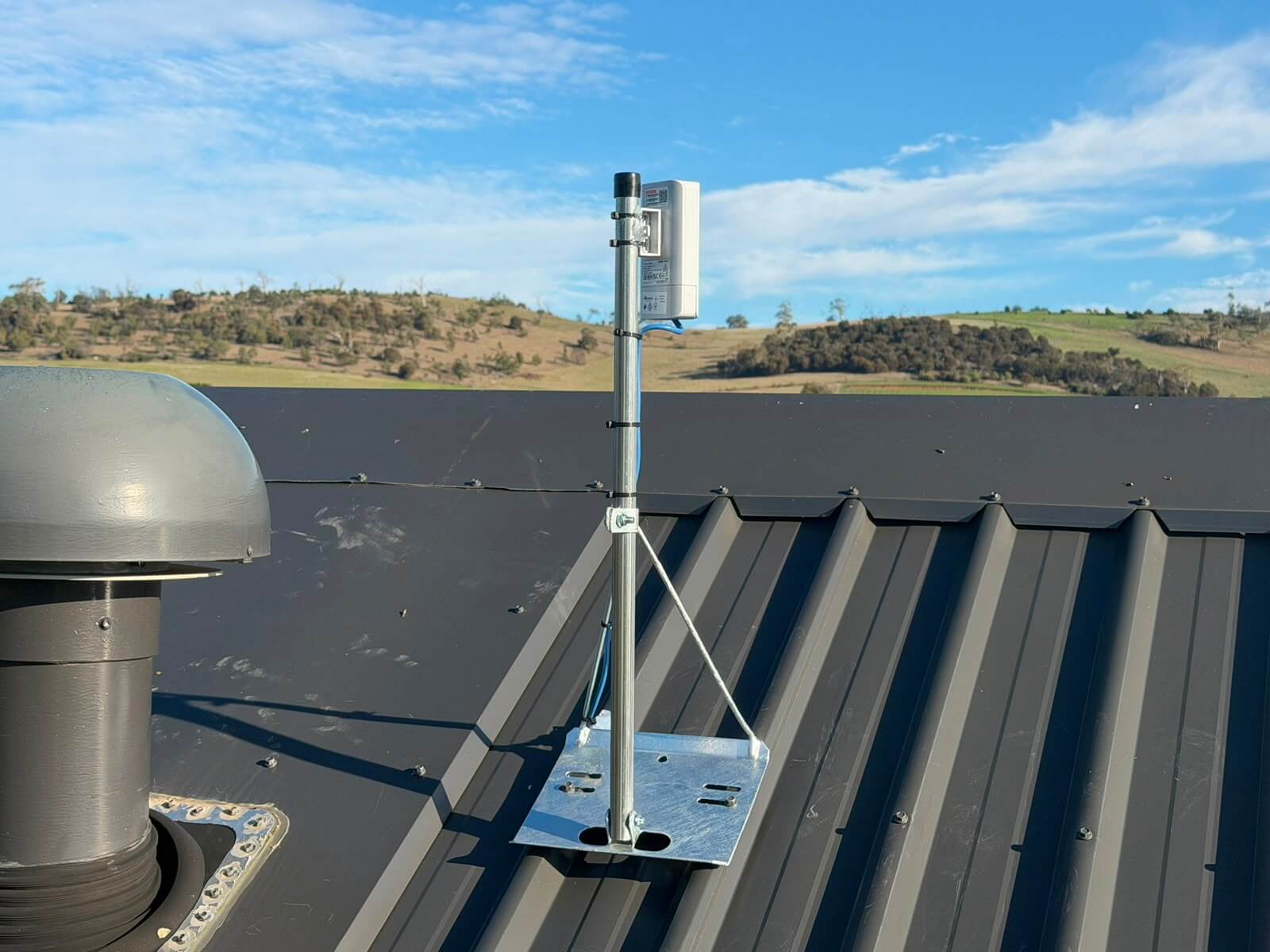 Point to point WiFi bridge mounted on a short mast on a Colorbond roof at Mapleton Vineyard, Tea Tree, Tasmania