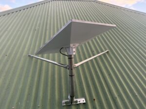 Starlink dish on a short braced pole mount on a green corrugated roof in Dodges Ferry, Tasmania