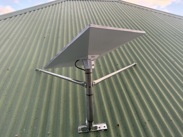 Starlink dish on a short braced pole mount on a green corrugated roof in Dodges Ferry, Tasmania