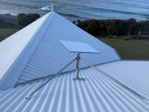 Starlink dish on a braced pole mount on a beachfront roof in Four Mile Creek, Tasmania