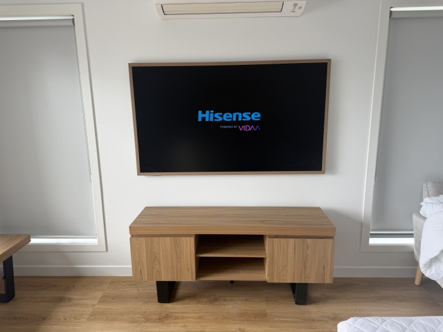 Picture frame style TV mounted flush on a wall above a timber TV unit in Lenah Valley, Tasmania